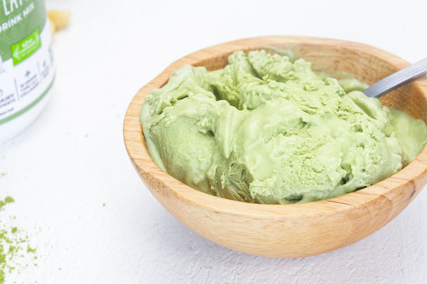 A wooden bowl filled with scoops of matcha ice cream. 