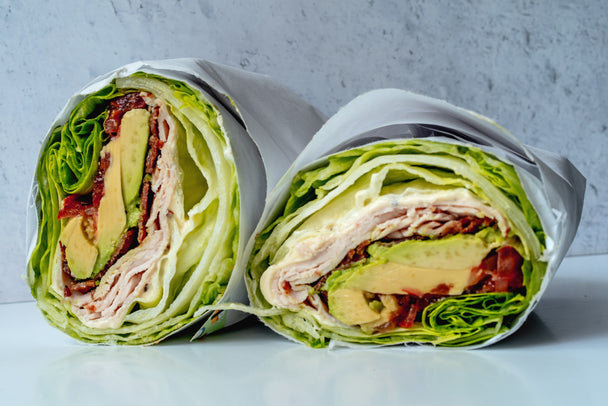 A turkey club lettuce wrap made with Primal Kitchen Garlic Aioli, cut in half