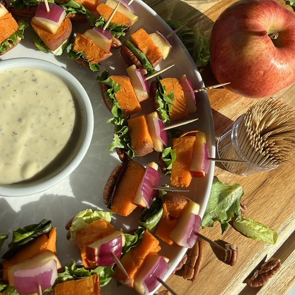 Closeup on a tray of autumn ranch bites with a ramekin of Primal Kitchen Ranch Dressing. An apple in the background. 