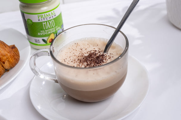  A mayo mocha coffee in a clear mug, with a jar of Primal Kitchen Mayo in the background.