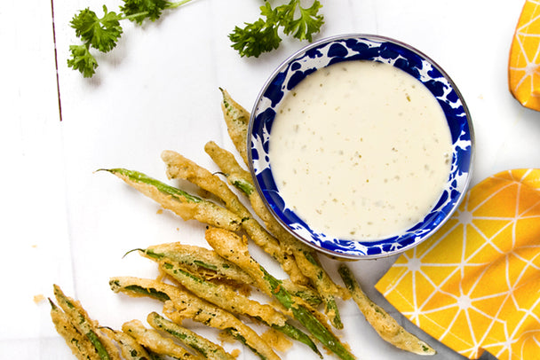 Tempura green beans next to a bowl of Primal Kitchen Ranch Dressing.