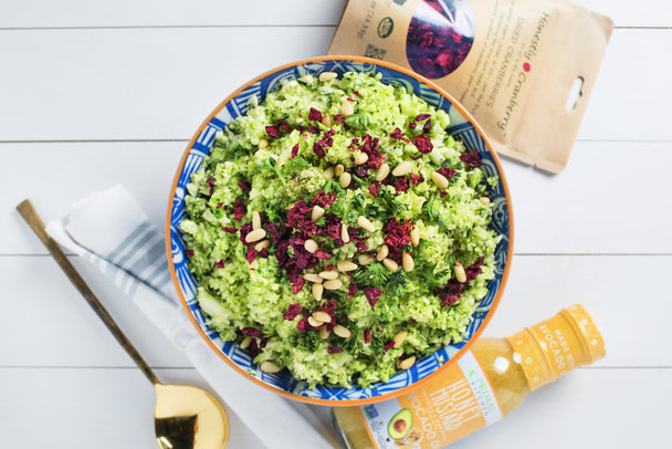 A bowl of zucchini rice, a bottle of honey mustard dressing, and a bag of cranberries.