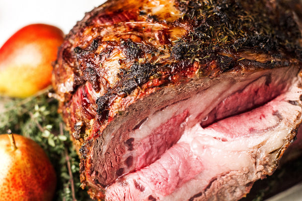 Closeup on a prime rib roast with a slice folded down. 