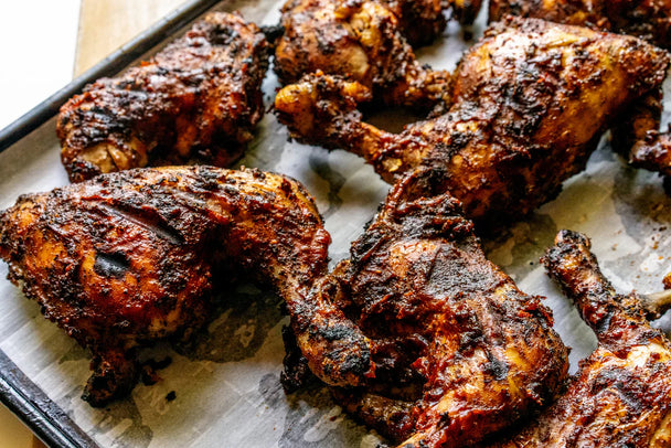 Grilled chicken pieces on a parchment lined tray.