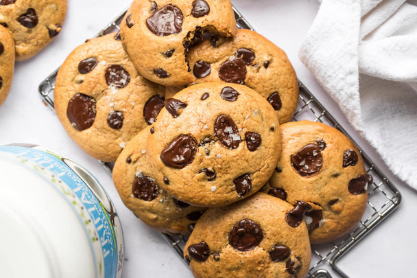 Chocolate chip protein cookies on a wire cooling rack with a canister of whey protein in the background.