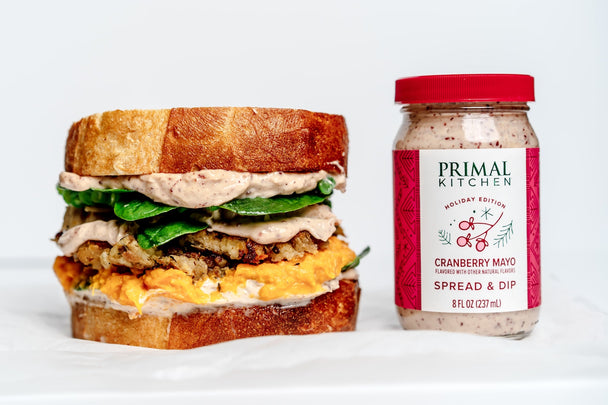 A leftover turkey sandwich next to a jar of Primal Kitchen Cranberry Mayo. 