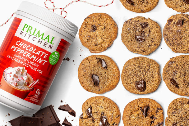 Overhead view of a tray of chocolate chunk cookies next to a canister of Primal Kitchen Chocolate Peppermint collagen. 