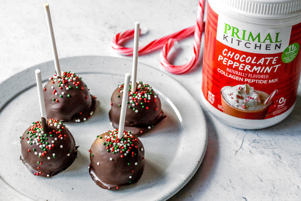 4 peppermint chocolate cake pops with sprinkles on a white plate next to a canister of Primal Kitchen Chocolate Peppermint Collagen. 