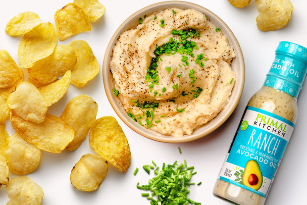 A bowl of potato chip mashed potatoes next to a bottle of Primal Kitchen Ranch dressing. 