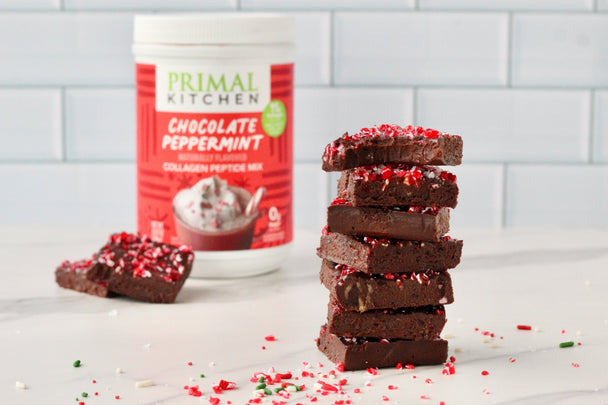 A group of peppermint fudge squares stacked next to a canister of Primal Kitchen Chocolate Peppermint Collagen.