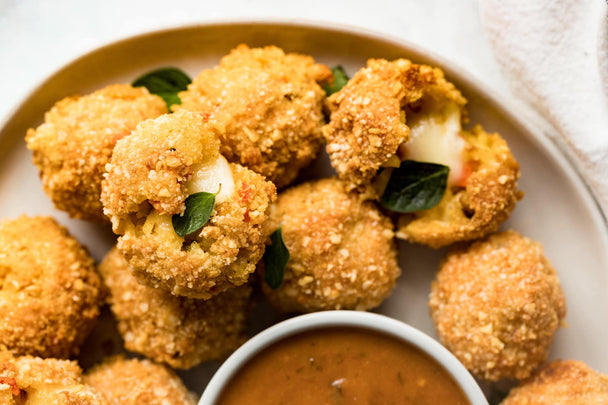 A plate of Italian rice balls with a ramekin of Primal Kitchen Sundried Tomato Sauce.