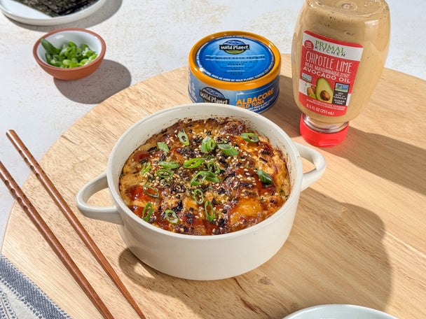 A ramekin of spicy sushi bake on a cutting board with a can of Wild Planet Tuna and a squeeze bottle of Primal Kitchen Chipotle Lime Mayo.