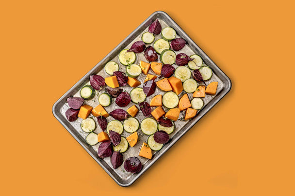 A tray of root vegetables on an orange background.