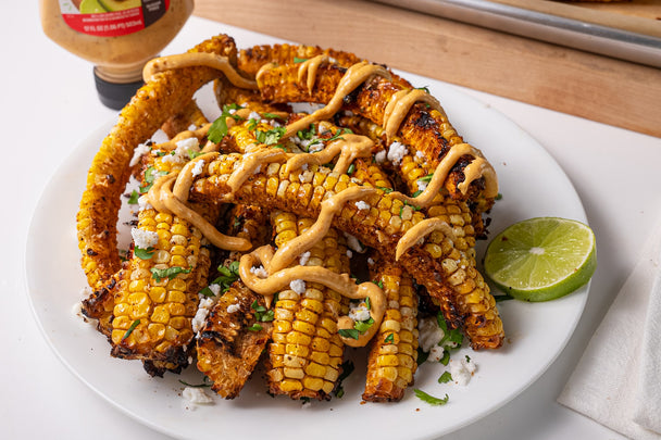 A plate of grilled corn ribs drizzled with Primal Kitchen Squeeze Chipotle Lime Mayo