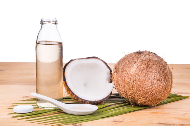 Coconuts next to a bottle of oil.