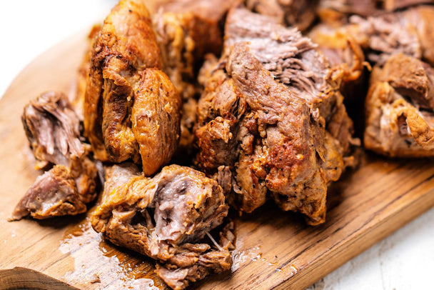 Keto pulled pork on a wooden cutting board.