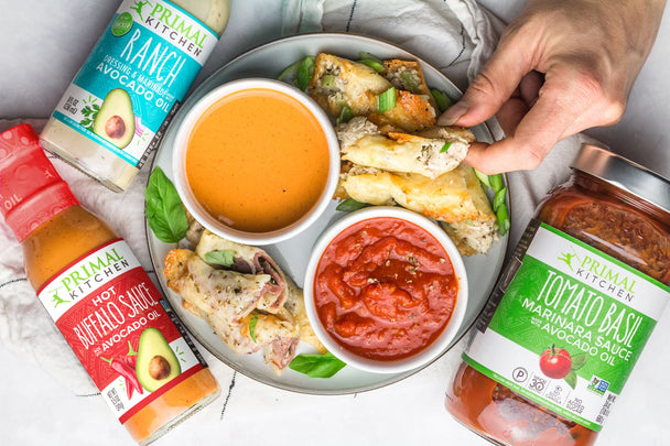 An easy keto snack, cheese roll ups, on a platter with Primal Kitchen sauces as dips.