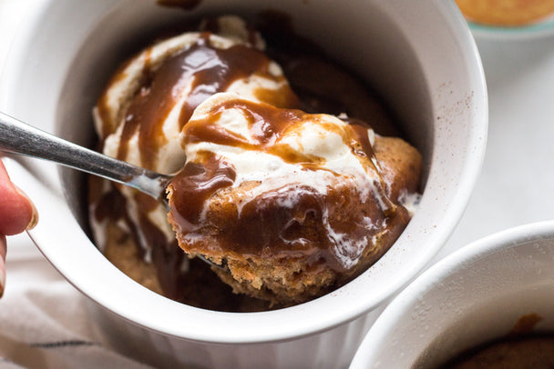 Spooning into a snickerdoodle mug cake topped with vanilla ice cream and drizzled caramel.