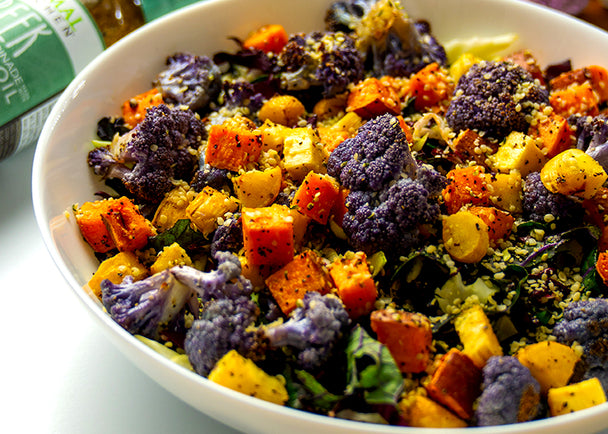 A dish with the colorful contents of the roasted veggie bowl next to greek dressing.