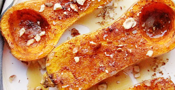 Three roasted butternut squash halves drizzled with maple syrup.