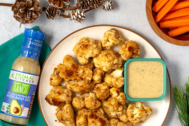 Cauliflower teriyaki bites on a white plate, with a side of Primal Kitchen Plant Based Ranch Dressing.