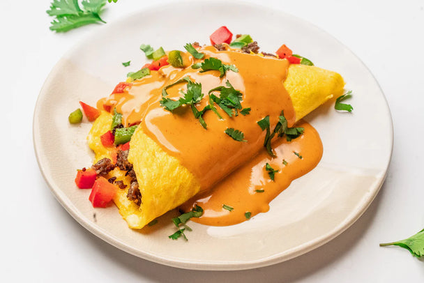 A Southwest Omelet is covered in Buffalo sauce, with a bottle of buffalo next to it.