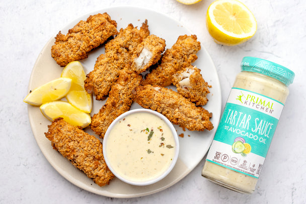 Air Fryer fish sticks on a white plate with Primal Kitchen Tartar Sauce and lemon slices