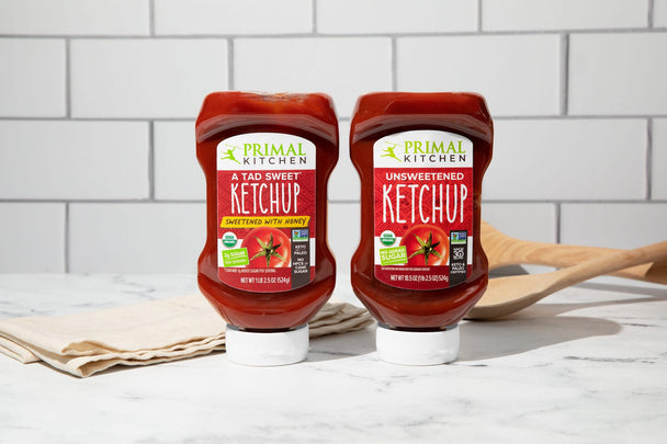 Two bottles of Primal Kitchen ketchup on a countertop.