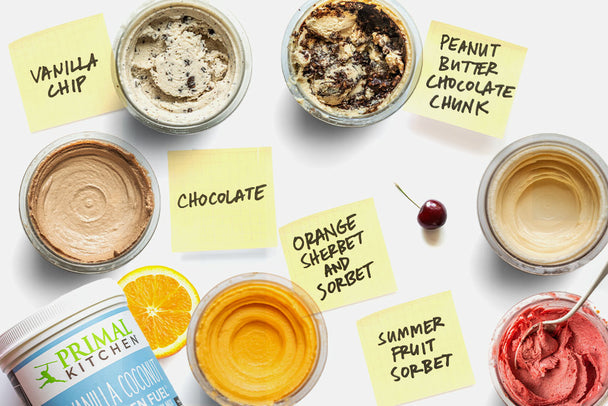 Overhead view of various jars of ice cream, with sticky note labels, fruits, and a canister of Primal Kitchen collagen in the background. 