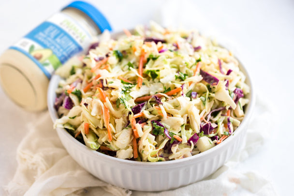 Closeup of spooning into a dish of Easy Coleslaw made with creamy Primal Kitchen Mayo. 