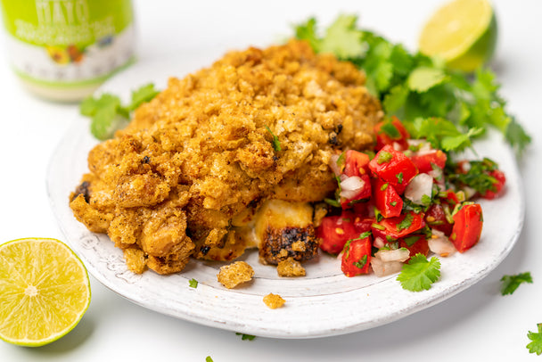 Keto Tex-Mex Stuffed Chicken Breast, cooked, on a white plate with pico de gallo, cilantro, and lime slices on the side