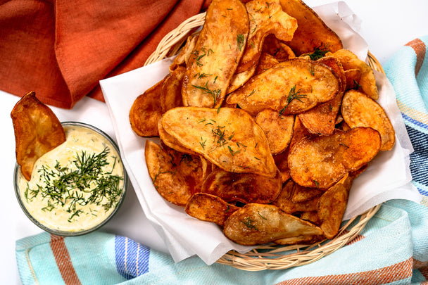 A bowl of crispy air-fried potato chips next to a bowl of Primal Kitchen Ranch Dip.