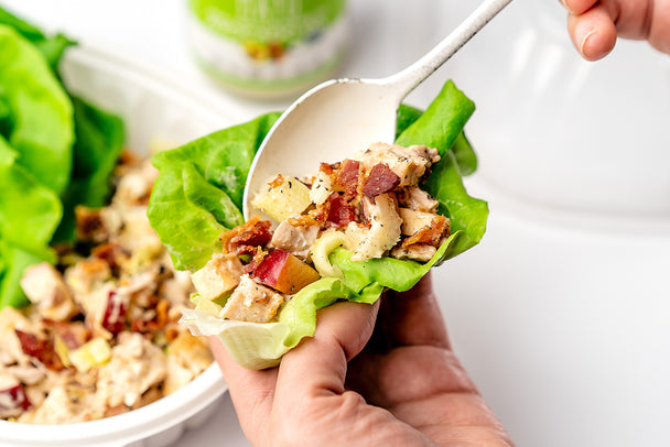 Spooning rotisserie chicken salad into a butter lettuce cup, with a hand holding the lettuce cup