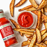 Primal Kitchen Ketchup next to a small bowl of ketchup and potato wedge fries.