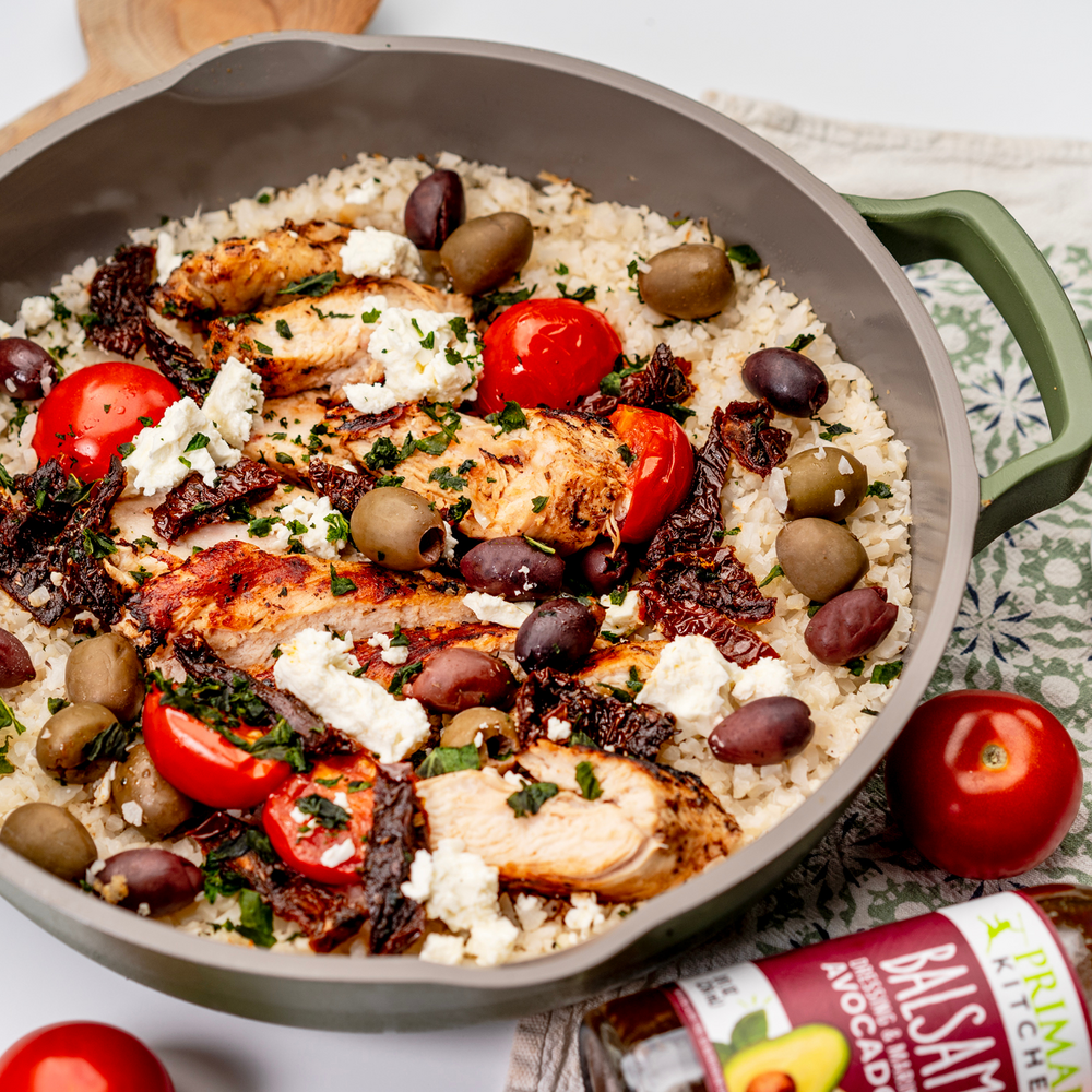 Primal Kitchen Balsamic Dressing with a skillet of Mediterranean Chicken.