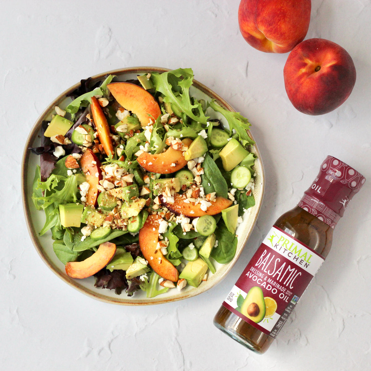 Peach and avocado Salad, topped with Primal Kitchen Balsamic Dressing and Marinade made with Avocado Oil.