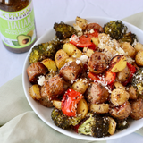 A bowl of sheet pan baked sausage, potatoes, and vegetables, marinaded in Primal Kitchen Italian Vinaigrette and Marinade made with Avocado Oil.