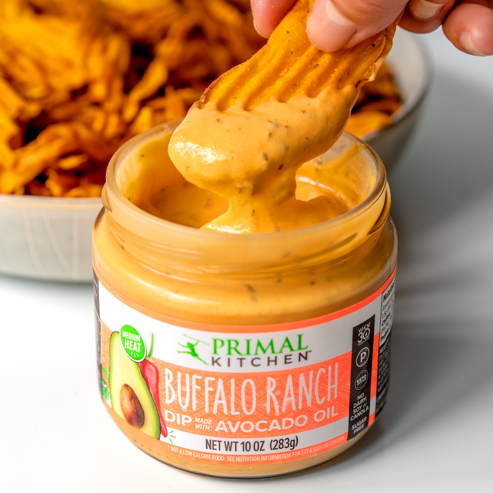 A chip being dipped into Primal Kitchen Buffalo Ranch Dip