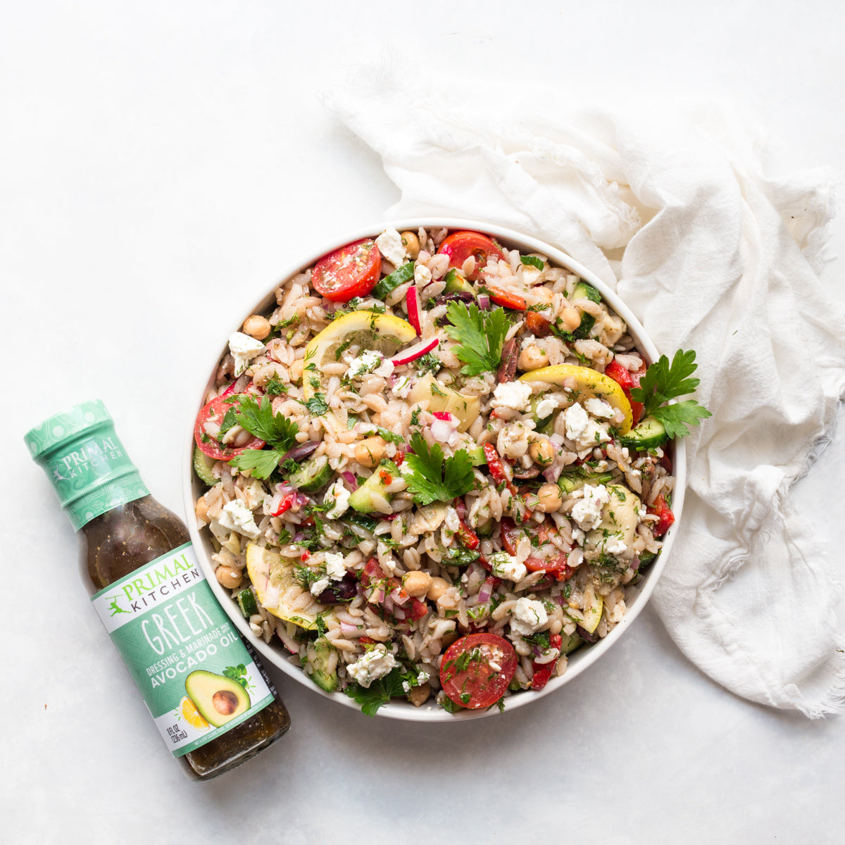 Greek orzo salad topped with Primal Kitchen Green Dressing & Marinade made with Avocado Oil