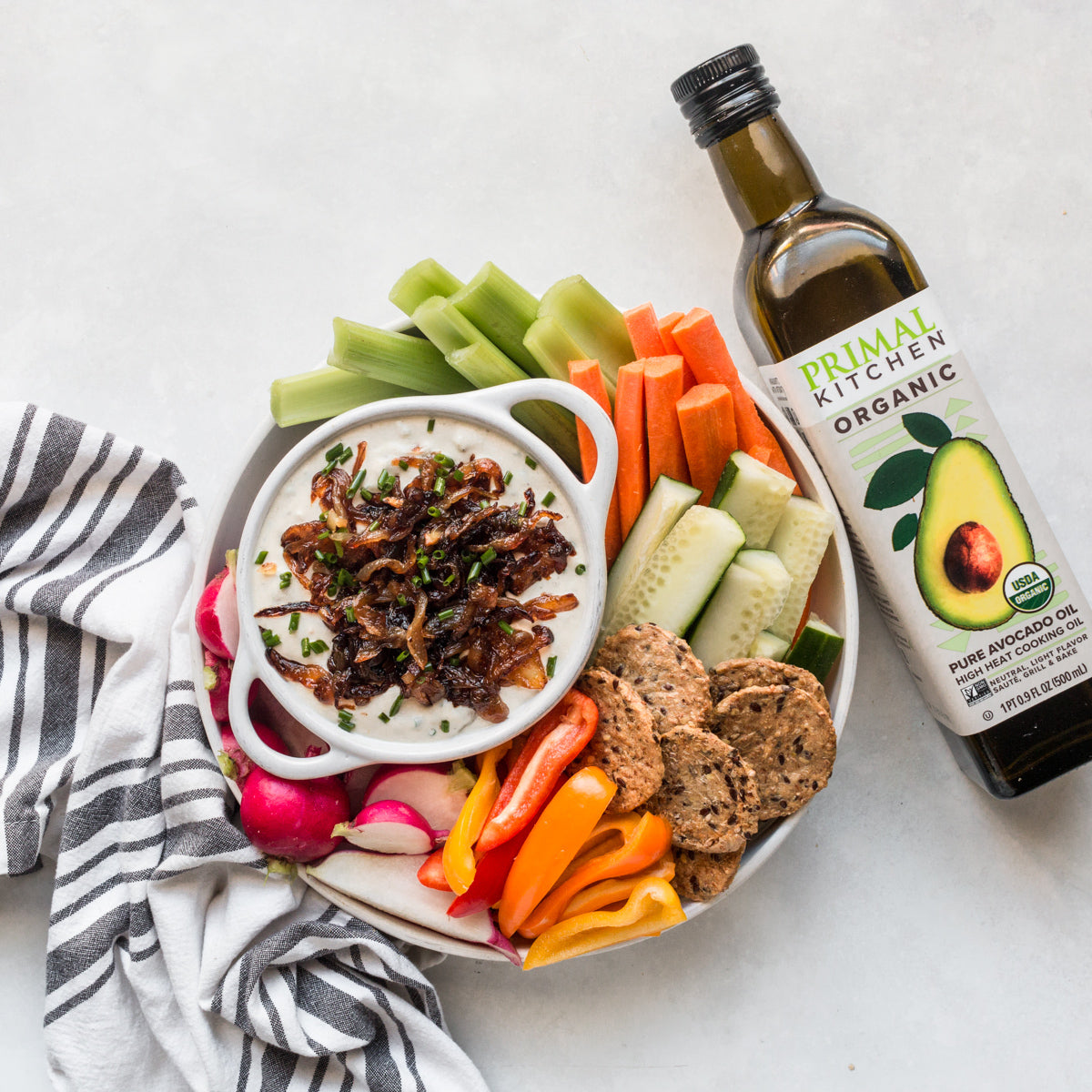 A bottle of Primal Kitchen Organic Avocado Oil next to a bowl of dip.